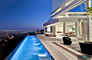 A luxury home with a pool overlooking the city at night, exclusively offered by a top real estate agent in Los Angeles.