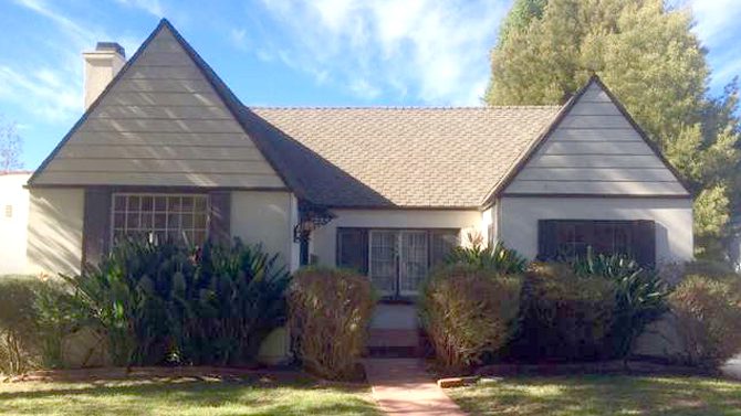 Looking for a Santa Monica Realtor? Look no further! This listing features a charming house adorned with a tin roof and surrounded by lush bushes. Contact us today for more information!