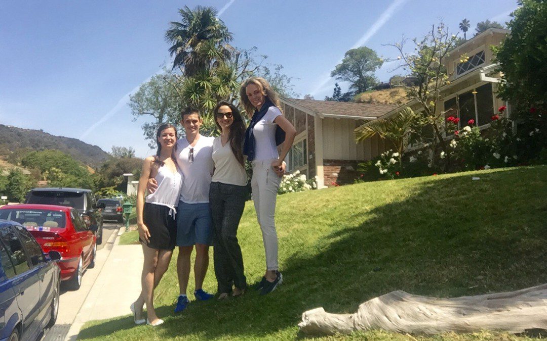 Four people posing for a picture in front of a house.
