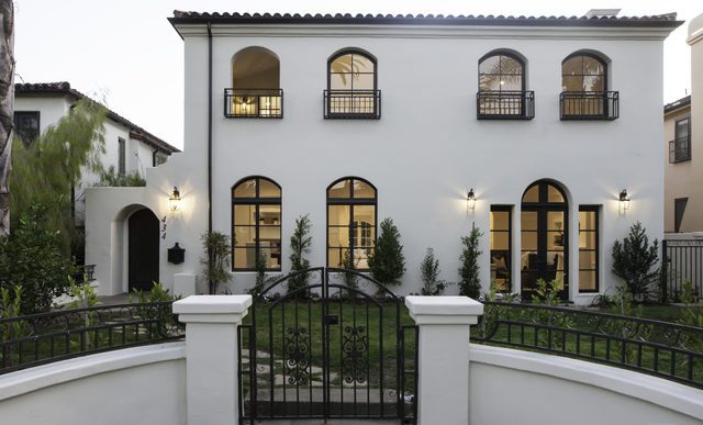 A white and black house with wrought iron gates.