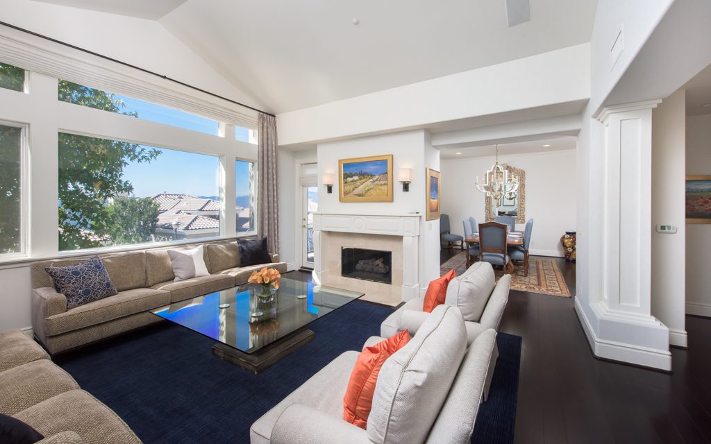 A living room with large windows and a fireplace.